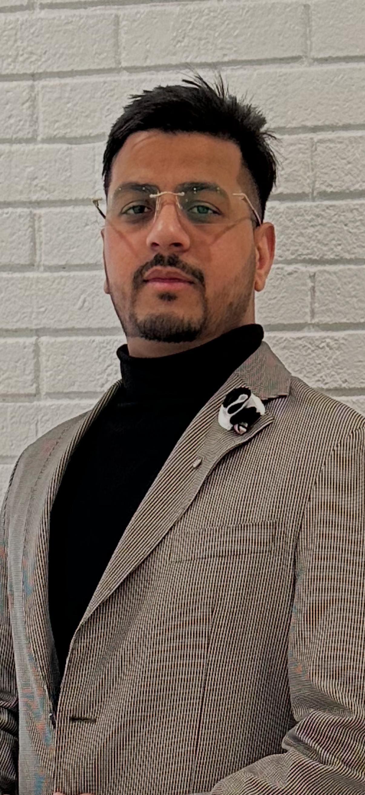 Sandeep, Co-Owner of Twins Leo Connection, in a grey jacket with glasses